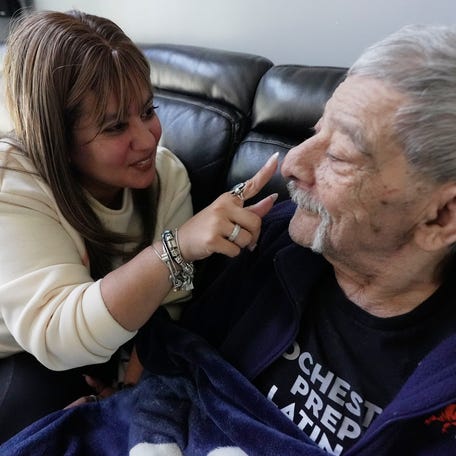 Jennifer Cortes takes care of her father, Julio Rivera, 82, who has dementia as well as other health issues, at her home in Rochester, NY on Sept. 11, 2025. After her father is up for the day, he stays downstairs so she, her husband or another family member can keep an eye on him. Her job as enrollment and transportation coordinator for Rochester Prep, which has seven charter schools teaching K-12 spread out throughout the city, offers her flexibility to work from home when she needs to.