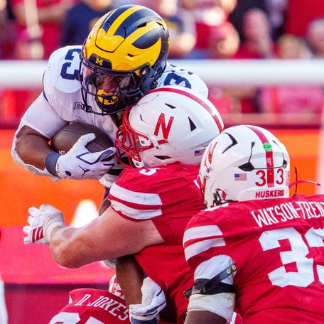 Michigan running back Jordan Marshall (23) leaps forward against Nebraska defensive lineman Riley Van Poppel (5), defensive back Donovan Jones (37), and linebacker Marques Watson-Trent (33) during the fourth quarter at Memorial Stadium.