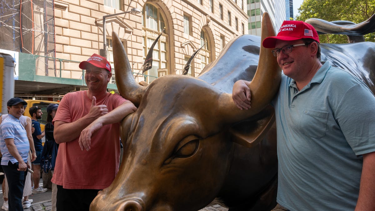 NEW YORK, NEW YORK - JULY 23: Donald Trump supporters stand with the Wall Street Bull on July 23, 2025 in New York City. The Dow rose over 500 points Wednesday as investors reacted to an announcement that Donald Trump has reached a trade deal with Japan. (Photo by Spencer Platt/Getty Images)