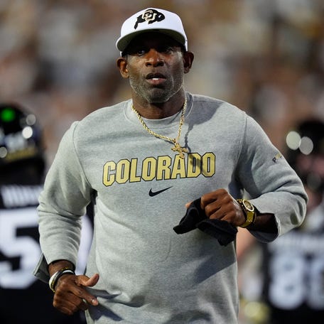 Colorado football coach Deion Sanders runs on the field before his team's game against Wyoming at Folsom Field.