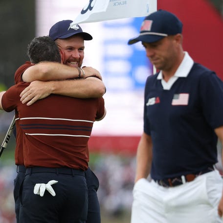 Team Europe's Shane Lowry celebrates with Rory McIlroy after winning the match on the 18th hole during the four-balls as Team USA's Justin Thomas walks past.