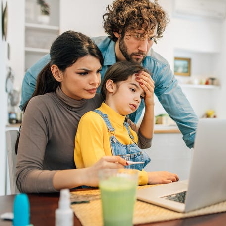 Worried parents on the computer with sick daughter