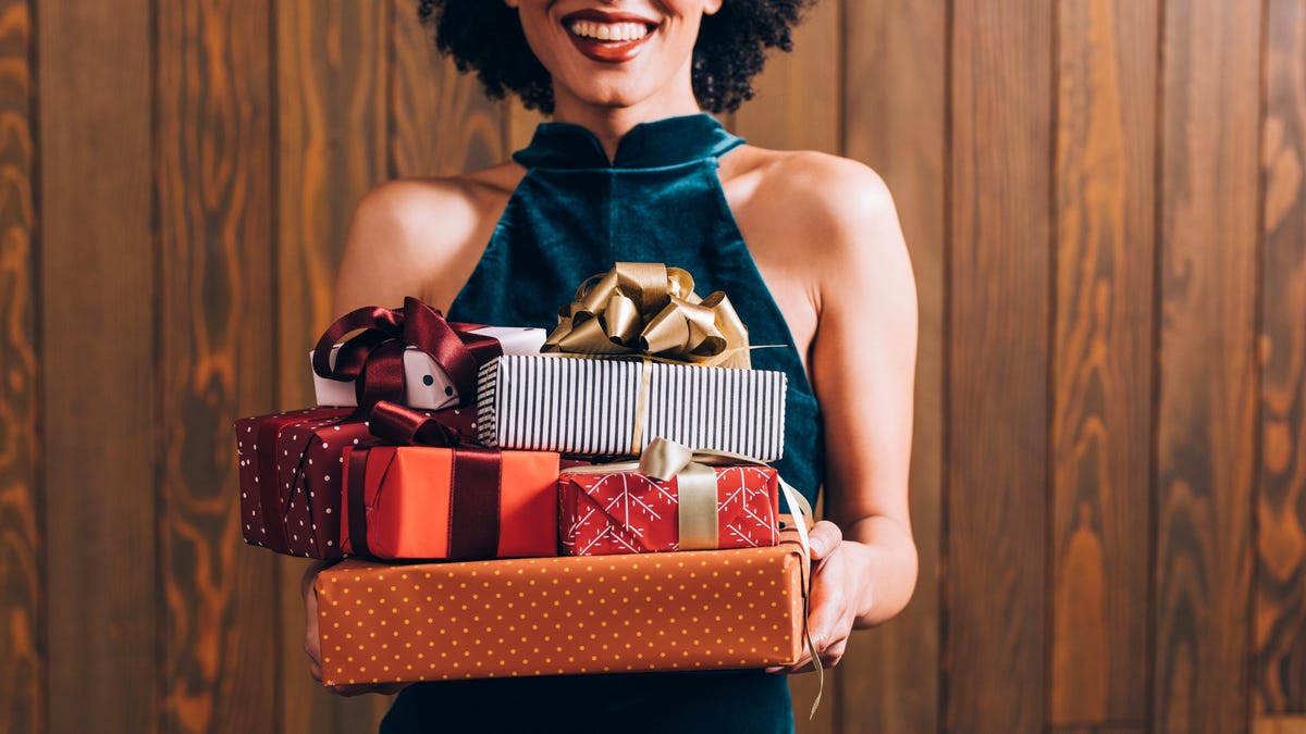 A woman holds presents in her hands.