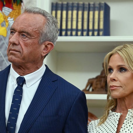 Robert F. Kennedy Jr. (left) and his wife Cheryl Hines listen to President Donald Trump before a swearing in ceremony for RFK Jr. in the Oval Office of the White House in Washington, DC, on Feb. 13, 2025.