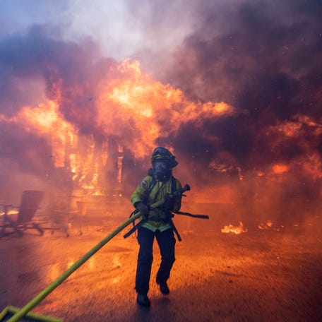 A firefighter battles the Palisades Fire as it burns during a windstorm on the west side of Los Angeles on Jan 7, 2025.