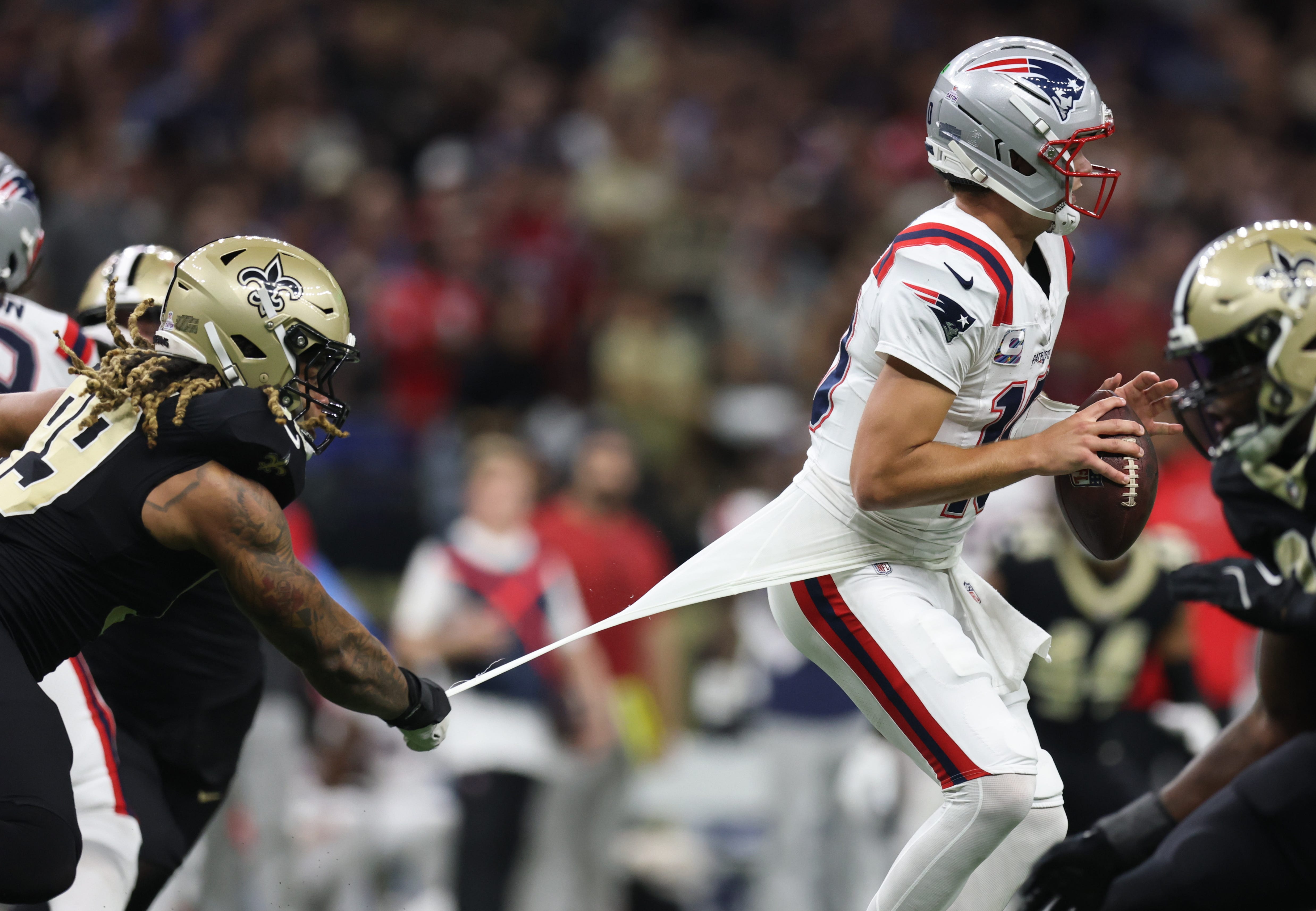 Oct 12, 2025; New Orleans, Louisiana, USA; New Orleans Saints defensive end Chase Young (99) pulls the shirt of New England Patriots quarterback Drake Maye (10) during the second half at Caesars Superdome. Mandatory Credit: Stephen Lew-Imagn Images