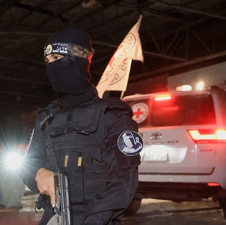 An armed Hamas militant stands guard as a Red Cross vehicle arrives in Gaza City on Oct. 14, 2025, to receive the bodies of deceased hostages who had been held in Gaza since October 7, 2023.