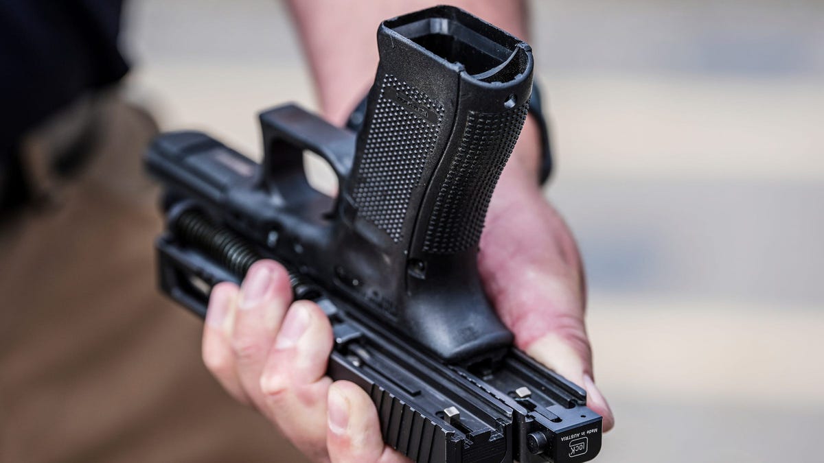 ATF Special Agent Kenton Weston holds two Glock handgun slides, one with a machine gun conversion switch, right, and one without, during a demonstration on the danger of such devices that make handguns fully automatic at the Canton Police Department training facility in Canton, Michigan, on Tuesday, July 23, 2024.