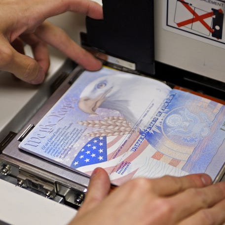 A US government official with the State Department's Passport Services places a new blank US Passport with an embedded electronic chip into the "book printer.