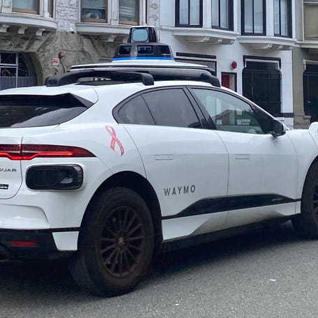 A Waymo self-driving taxi cruises up Pine Street in San Francisco this summer.