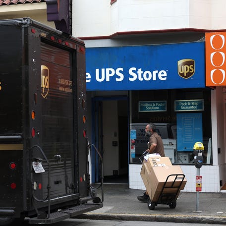 A UPS driver pulls a cart with packages while making deliveries on June 12, 2023 in San Francisco, California.