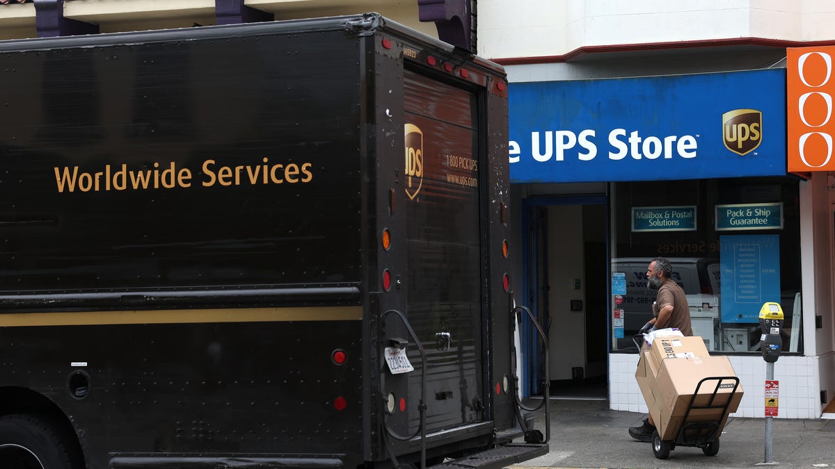 A UPS driver pulls a cart with packages while making deliveries on June 12, 2023 in San Francisco, California.