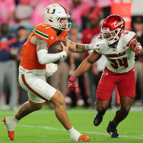 Oct 17, 2025; Miami Gardens, Florida, USA; Miami Hurricanes quarterback Carson Beck (11) carries the football against Louisville Cardinals linebacker T.J. Quinn (34) during the third quarter at Hard Rock Stadium. Mandatory Credit: Sam Navarro-Imagn Images