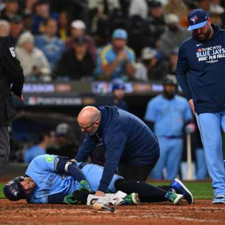 Toronto Blue Jays designated hitter George Springer (4) is helped by training staff after getting hit by a pitch against the Seattle Mariners.