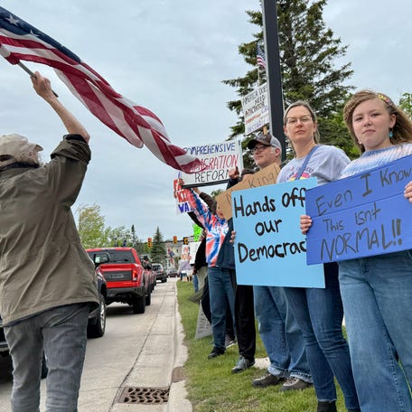 Demonstrators of all ages line U.S. 31 in downtown Petoskey during the No Kings Day protest on June 14, 2025 holding handmade signs and waving flags as cars honked in support.