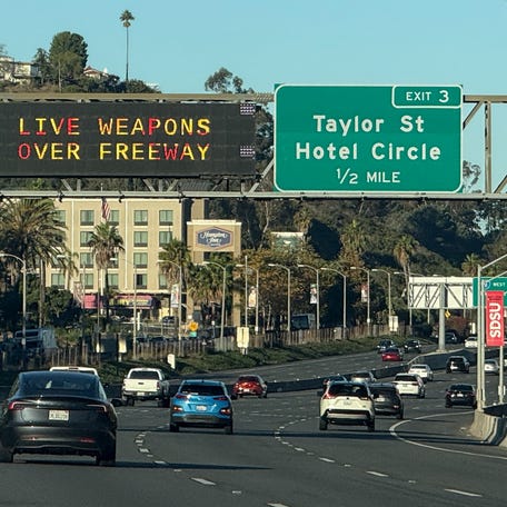Freeway signs warn drivers on Interstate 8 approaching Interstate 5 of "Live Weapons Over Freeway" in San Diego, California on October 18, 2025.