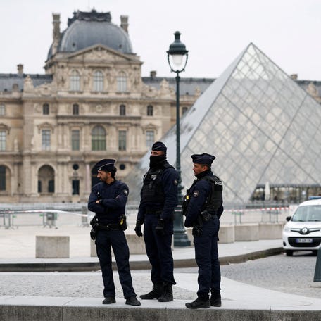 Police officers stand near the pyramid of the Louvre museum after reports of a robbery, in Paris, France, October 19, 2025. REUTERS/Gonzalo Fuentes