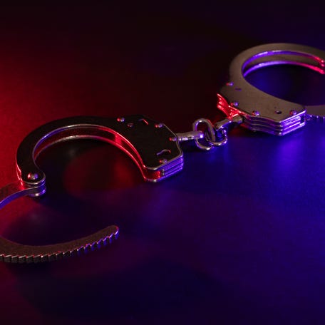 Closed handcuffs on the street pavement at night with police car lights high contrast image.