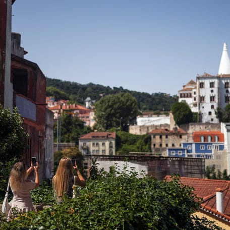 Tourists take pictures of Sintra National Palace in Sintra on August 10, 2025.