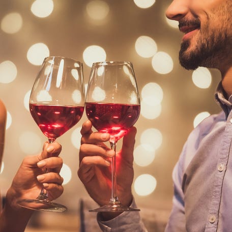 A young couple on a date clinking their glasses of wine together.