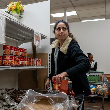 Maryan Yousef, a first-time volunteer, helps stock the shelves at Capuchin Soup Kitchen in Detroit on Friday, Oct. 24, 2025.
