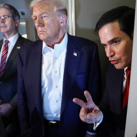 U.S. Secretary of State Marco Rubio gestures while standing near U.S. President Donald Trump and U.S. Treasury Secretary Scott Bessent onboard Air Force One while on their way to Tokyo, Japan, for the second stop on his Asia tour, October 27, 2025.