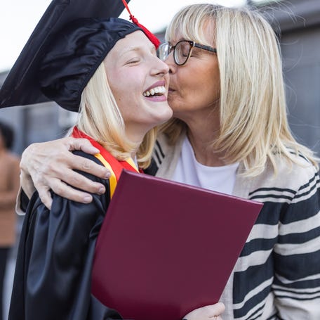 Graduation day. Mother congratulating graduating daughter.