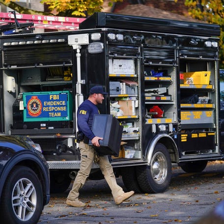 A member of the FBI is seen carrying an item from a home on Horger St. in Dearborn on Friday, Oct. 31, 2025.