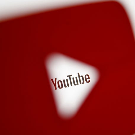 A 3D-printed YouTube icon is seen in front of a displayed YouTube logo.