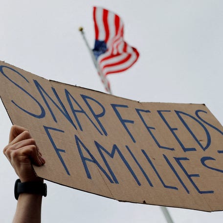 A man holds a sign reading "SNAP Feeds Families," as food aid benefits will be suspended starting November 1 amid the ongoing U.S. government shutdown, during "A Rally for SNAP" on the steps of the Massachusetts Statehouse in Boston, Massachusetts, U.S., October 28, 2025.