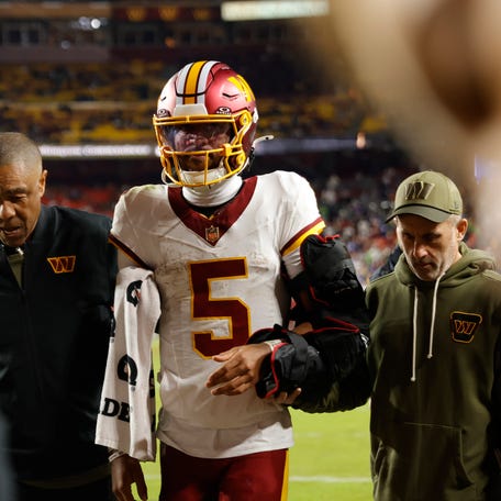 Jayden Daniels is helped off the field after an injury.