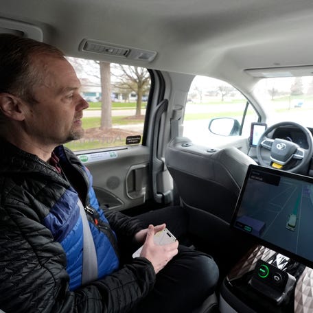Edwin Olson, the CEO and co-founder of May Mobility, watches from the second row as a driverless Toyota Sienna moves around Ann Arbor during a demonstration drive for the Detroit Free Press on Wednesday, April 9, 2025. The minivan's driver's seat remains empty. The computer controls and navigation equipment are stored on the front passenger seat, leaving the second and third row seats for passengers.