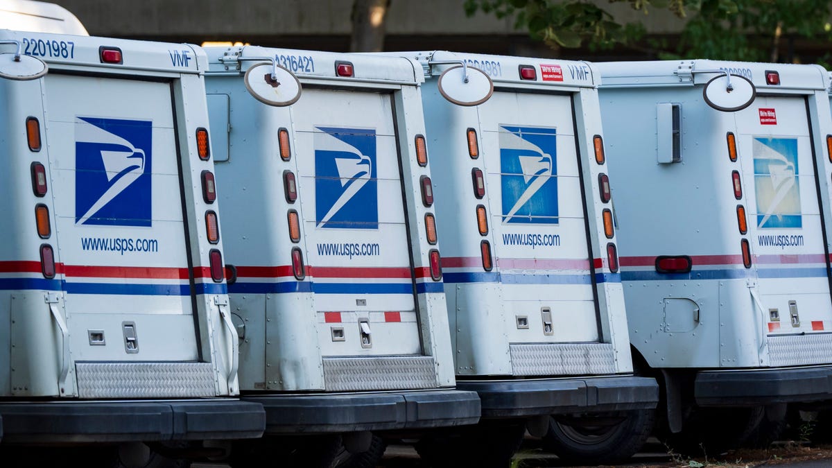 Mail trucks line the parking lot at the downtown Eugene Post Office on Aug. 21, 2025.