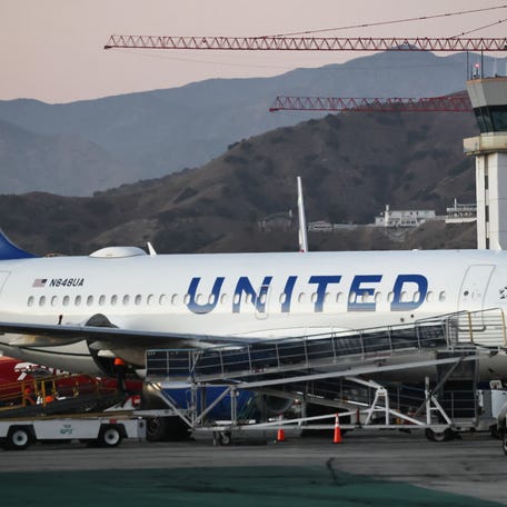 The Hollywood Burbank Airport air traffic control tower stands beyond a parked United Airlines plane on October 6, 2025 in Burbank, California.