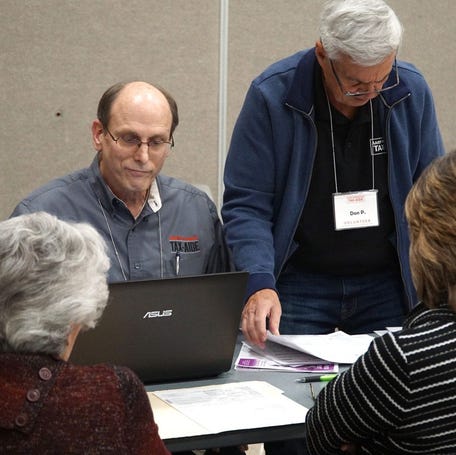 Tax Aide Jack Motz, left, helps to check the tax-filings of some visitors to AARP's free 2018 tax filing gathering on March 13 at the Novi Civic Center.     Noviciviccenterbusyday6