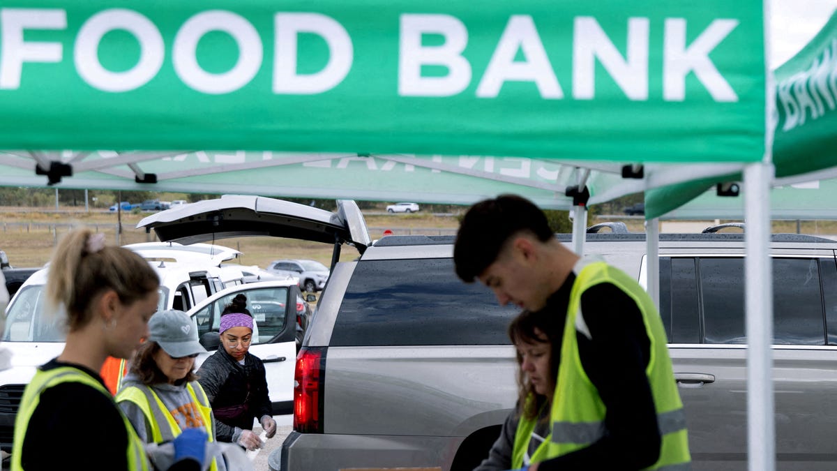 Volunteers place food items in vehicles during a mobile food distribution at Cedar Creek High School, as nearly 42 million Americans face a potential lapse in Supplemental Nutrition Assistance Program (SNAP) benefits, known as food stamps, due to the second-longest U.S. government shutdown, in Cedar Creek, Texas, U.S., November 1, 2025.