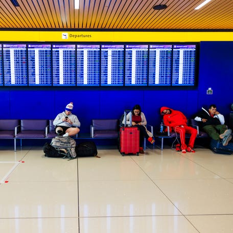 DENVER, COLORADO - NOVEMBER 8: People sit under a display board at Denver International Airport on November 8, 2025 in Denver, Colorado. The FAA has targeted 40 "high-volume" airports, including Denver International Airport, for flight cuts amid the government shutdown. (Photo by Michael Ciaglo/Getty Images)