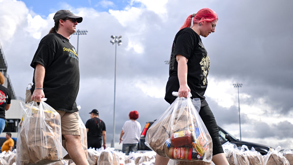 People carry bags of groceries during a free food distribution for recipients of the Supplemental Nutrition Assistance Program (SNAP) organized by the Volusia County Sheriff's Office and The Jewish Federation at the Daytona International Speedway in Daytona Beach, Florida, on November 9, 2025. The US Supreme Court said on November 7 that the Trump administration does not have to immediately pay SNAP food benefits defunded during the government shutdown, a temporary order that   leaves millions in limbo.