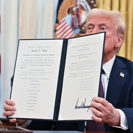 President Donald Trump holds up an executive order at the White House in Washington, DC, on Jan. 23, 2025, to pardon anti-abortion activists convicted of blockading abortion clinic entrances.