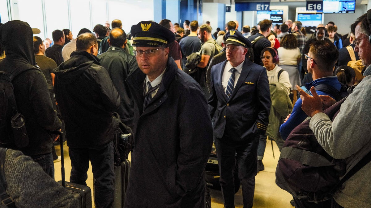 Pilots stand among passengers waiting at crowded gates as flight delays persist amid FAA measures more than a month into the ongoing U.S. government shutdown, at O'Hare International Airport in Chicago, Illinois, on Nov. 10, 2025.
