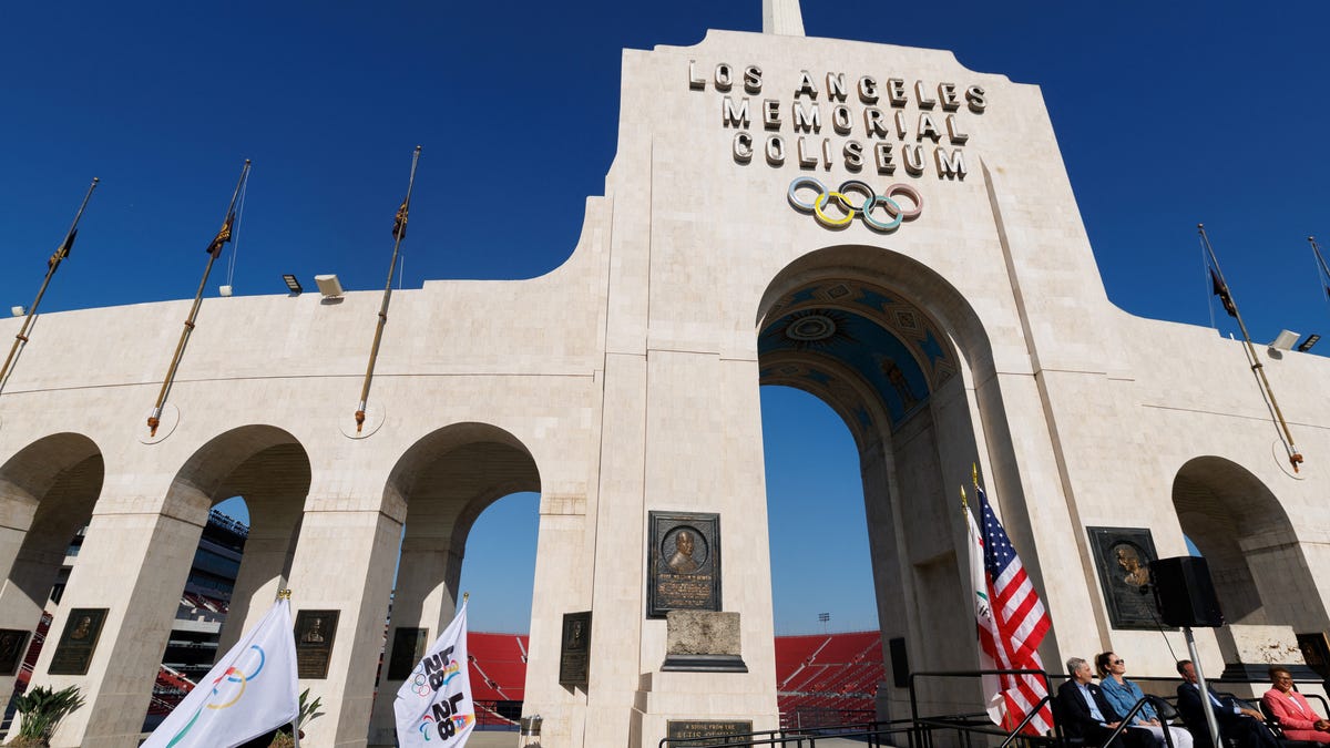 LA28 workers carry Olympic flags on the day of a ceremony to announce the locations for the opening and closing of the Olympic and Paralympic games, in Los Angeles, California, U.S., May 8, 2025.