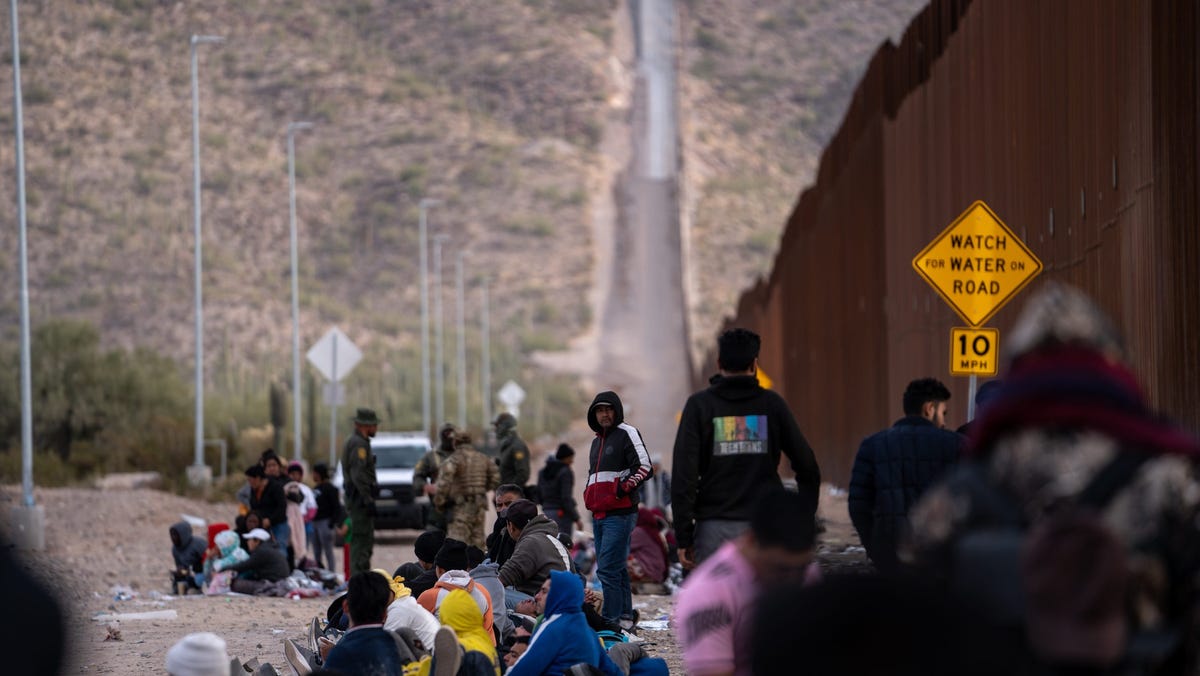 Migrants and asylum seekers wait to be picked up and processed by U.S. Border Patrol agents in Organ Pipe Cactus National Monument along the U.S.-Mexico border about a mile west of Lukeville on Dec. 4, 2023. The Lukeville Port of Entry was closed indefinitely by officials Dec. 4.