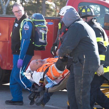 A victim from a trench collapse on South South Shore Drive that trapped him for hours reaches out to shake hands with one of his co-workers as he is wheeled to a waiting ambulance at the ongoing sewer construction project near Parkers River Beach.  Photo taken on November 18, 2025