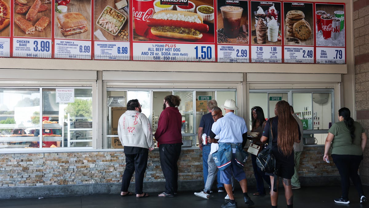 Customers wait in line to order below signage for the Costco Kirkland Signature $1.50 hot dog and soda combo, which has maintained the same price since 1985 despite consumer price increases and inflation, at a food court outside a Costco Wholesale warehouse store in Hawthorne, California on August 27, 2025.