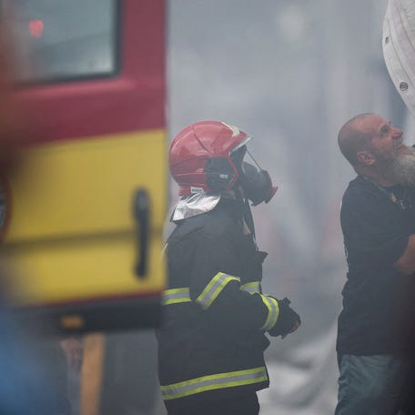 A firefighter stands next to a man removing a tent cover due to a fire alert during the UN Climate Change Conference (COP30), in Belem, Brazil, November 20, 2025. REUTERS/Adriano Machado.