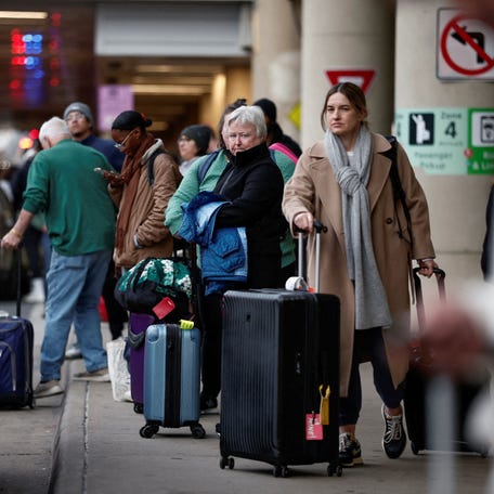 Travelers wait at a ride-sharing and taxi pickup area at Ronald Reagan National Airport on Nov. 27, 2024.