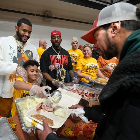 Joyner Lucas, who was hosting his "Thanksgiving Joyner Feast" at the YMCA, watches as his son, Joyner Lucas Jr., serves mashed potatoes to Erik Capo, 45, of Worcester.