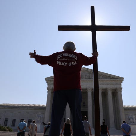 A demonstrator holds a large cross outside the U.S. Supreme Court on July 8, 2020.