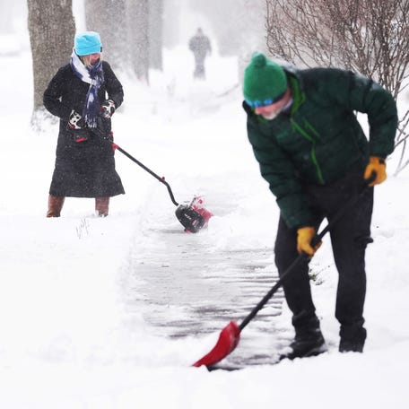 Keiva Delaney cleans snow from a sidewalk on Hodge Avenue during a winter storm on Nov. 29, 2025, in Ames, Iowa.