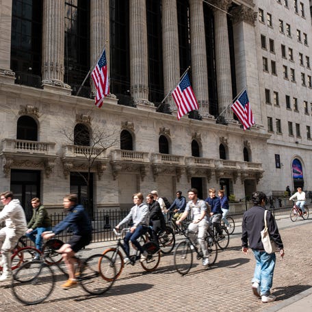 Tourists ride bicycles past the New York Stock Exchange in lower Manhattan on March 28, 2025, in New York City.